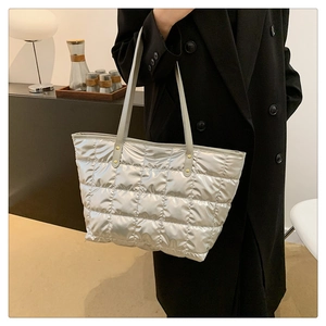 Close-up of metallic silver quilted tote bag with soft padded texture and grey handles