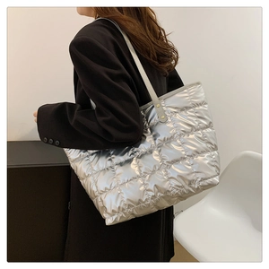 Detailed view of large metallic silver tote bag with quilted square texture on a shoulder