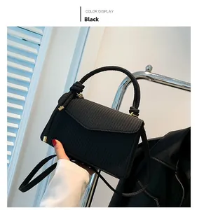 Detail of black woven shoulder bag featuring a knotted handle and V-shaped flap