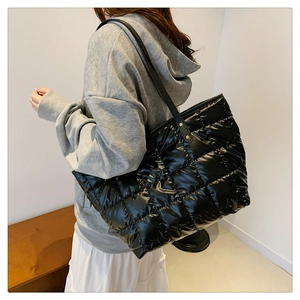 Detail of black glossy quilted tote bag showing large capacity and shoulder strap texture