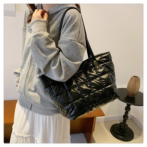 Détail d'un sac cabas noir matelassé montrant la texture brillante et le motif en losange
