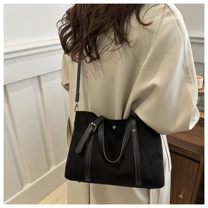 Detail of black matte tote bag with leather trim worn on shoulder for commute