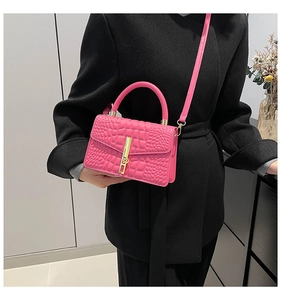 Détail du sac rose vif à motif crocodile avec fermoir doré et poignée supérieure chic