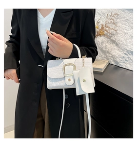 Detail of white crocodile pattern handbag with gold buckle and matching mini pouch