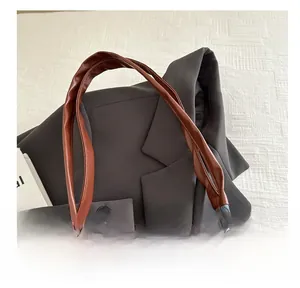 Dettaglio borsa tote in denim blu con comodi manici in pelle marrone e trama di alta qualità