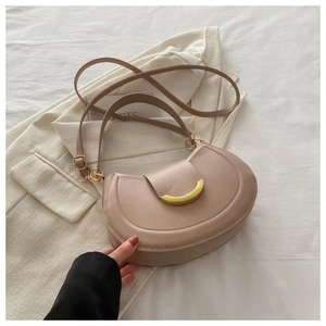 Dettaglio borsa a mezzaluna rosa cipria con fibbia oro su un completo color beige