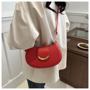 Borsa a sella in pelle rossa con fibbia dorata indossata da modella in un caffè