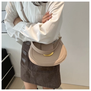 Borsa a tracolla a mezzaluna beige con fibbia dorata indossata per uno stile casual