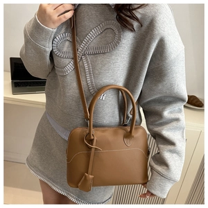 Detail of brown leather handbag with contrast white stitching and top handles on desk