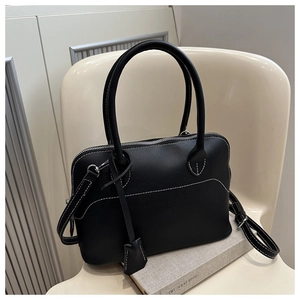 Detail of black leather tote bag featuring white contrast stitching and adjustable strap