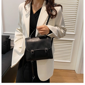 Classic black British style satchel with double buckle closure on white blazer