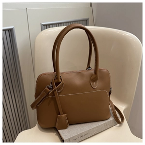 Close-up of brown tote bag featuring white contrast stitching and silver hardware detail