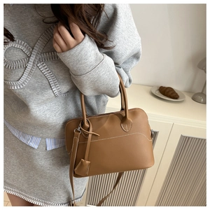 Detail of caramel leather handbag showing contrast white stitching and pebbled texture