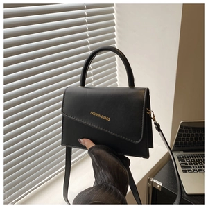 Close-up of black leather crossbody bag with hard handle and golden Fashion & Bags text