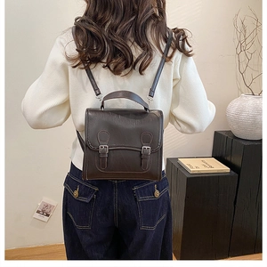 Detail view of a vintage dark brown leather backpack with silver buckles on a model