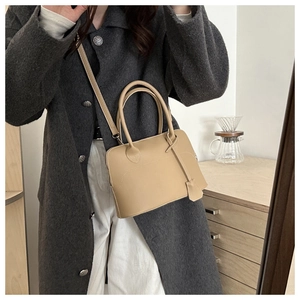 Detail of tan leather tote bag with cylindrical handles and detachable shoulder strap