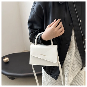 Detail of white leather handbag with gold Fashion & Bags lettering and top handle