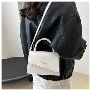 Minimalist white leather crossbody bag with asymmetric fold design and gold lettering