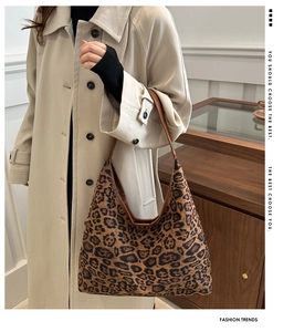 Detail of a large leopard print tote bag with brown leather handles and autumn trench coat