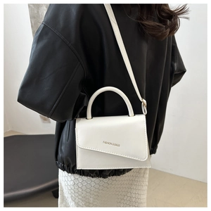 Detail of white leather handbag with asymmetric flap and fashion logo lettering