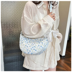 Floral canvas half-moon bag worn as an underarm shoulder bag with lace bow detail
