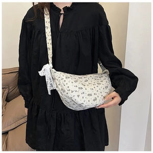 Detail of floral canvas crescent bag featuring white lace bow and black flower print