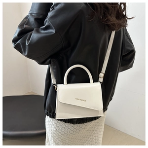 Detailed shot of white minimalist handbag featuring gold FASHION & BAGS lettering