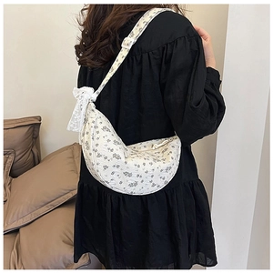 Close-up of floral canvas hobo bag with lace bow detail worn by a model