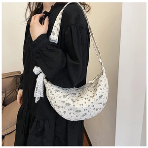 Close-up of floral canvas crescent bag featuring delicate white lace bow detail