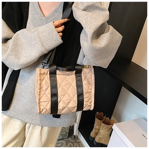 Detail of champagne quilted nylon tote bag with black strap and detachable shoulder strap