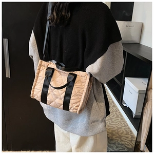 Détail du sac cabas matelassé beige avec poignées noires contrastées sur mannequin