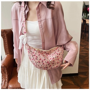 Detail of pink floral dumpling bag featuring a delicate white lace bow and wide strap