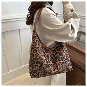 Leopard print hobo bag with brown leather trim worn by a model in a minimal setting
