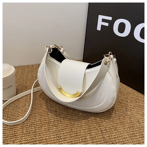 Borsa a tracolla bianca a mezzaluna in pelle con chiusura dorata su sfondo marrone