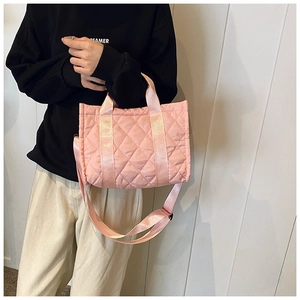 Sac fourre-tout matelassé rose à motif de losanges porté par un mannequin en tenue décontractée