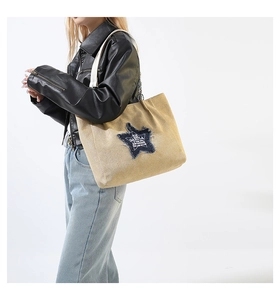 Detailed view of large khaki canvas tote bag with denim star patch and metal chain strap