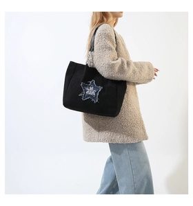 Detail of black suede tote with star patch and metal chain strap on model