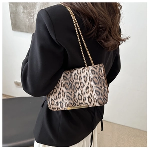 Détail du sac à rabat léopard avec fine chaîne dorée et garniture métallique sur un mannequin