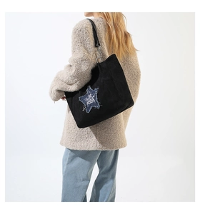 Detail of black canvas tote featuring blue denim star patch with silver chain strap