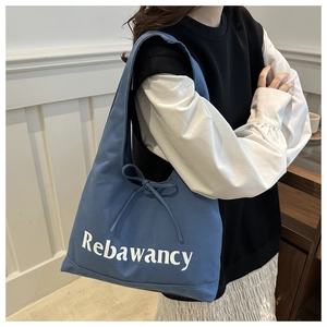 Close-up of blue canvas tote bag with white lettering and a stylish ribbon bow detail