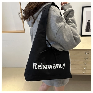 Detail view of black canvas tote bag with white lettering and side ribbon strap