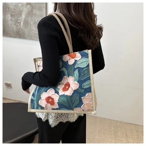 Artistic oil painting floral tote bag with thick woven handle shown on model shoulder