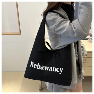 Detail van een grote zwarte canvas tas met witte belettering en decoratief trekkoord