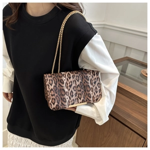 Detail of leopard print crossbody bag with gold chain strap on a female model
