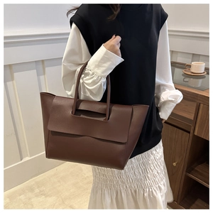 Detail of soft dark brown leather tote bag held by model for daily commute style