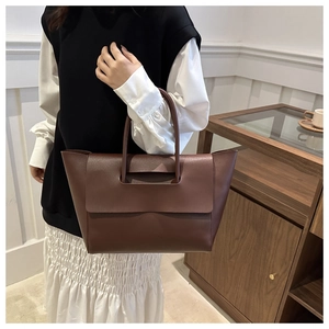 Close-up of the smooth dark brown leather texture and buckle detail on a tote bag