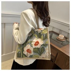 Detalle de bolso tote étnico de flores con correas tejidas sobre una chaqueta blanca
