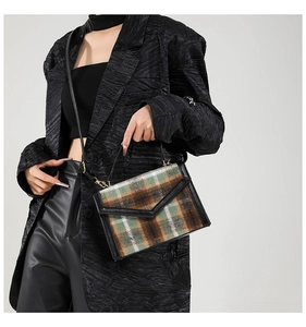 Détail du sac à rabat vintage à carreaux avec bordure en cuir noir sur un blazer texturé