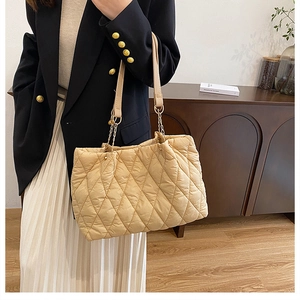 Dettaglio della borsa tote trapuntata beige con motivo a rombi e tracolla a catena