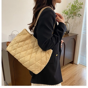 Detail of beige quilted tote bag featuring elegant gold chain accents on the strap